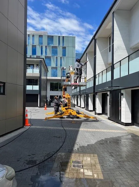 WashNZ spider lift working in the courtyard of an apartment complex