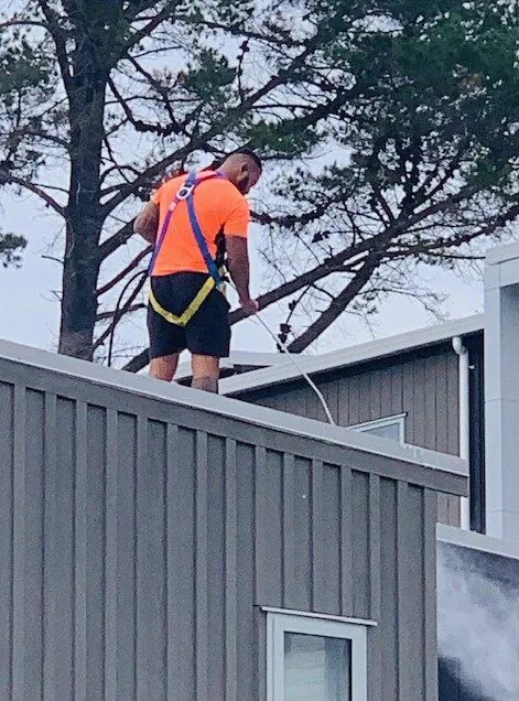 Technician in a harness at roof height