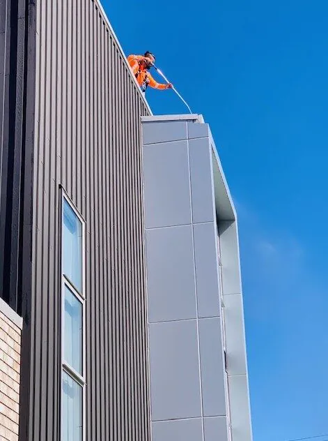 Technician washing an upper-storey wall
