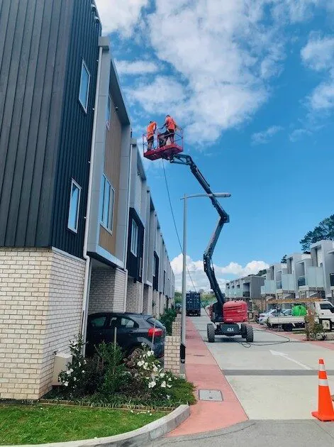 WashNZ elevated work platform washing a townhouse on a street corner